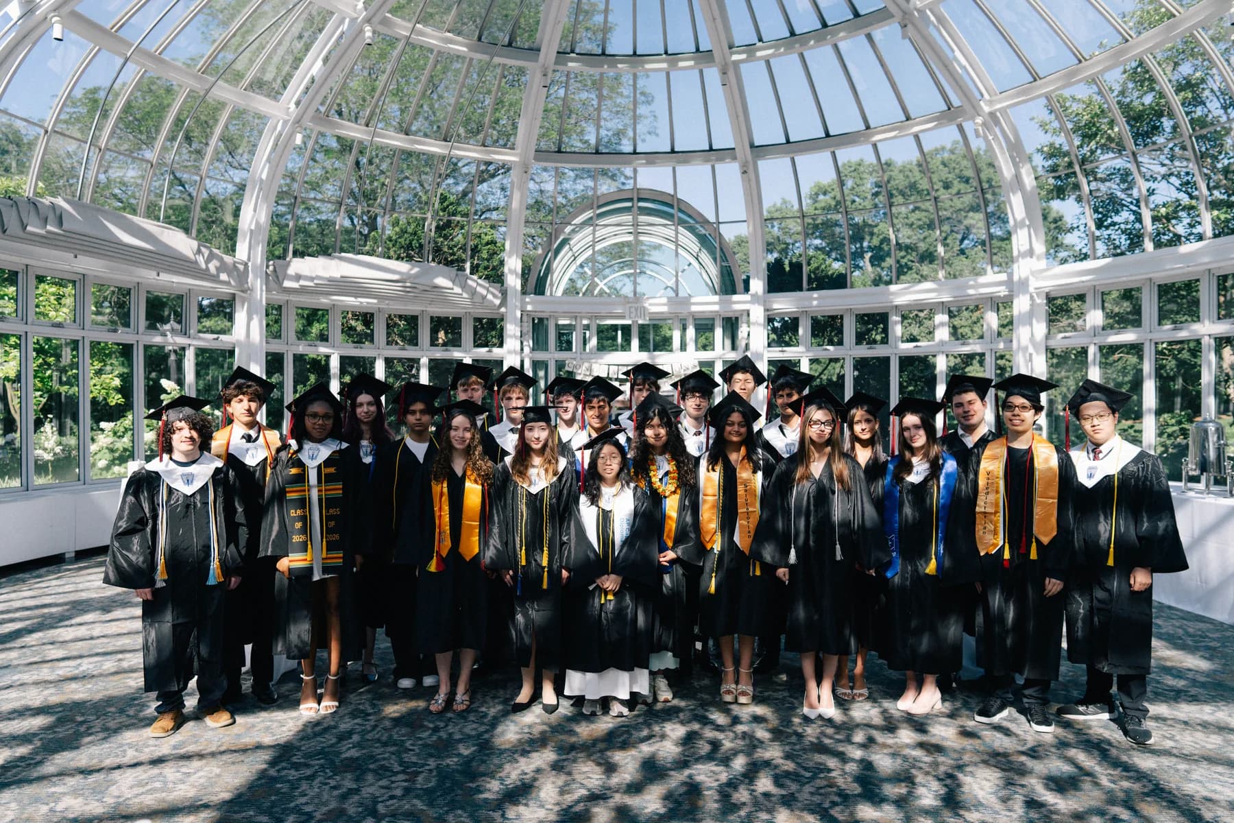 The graduating class at a ceremony in a glass conservatory
